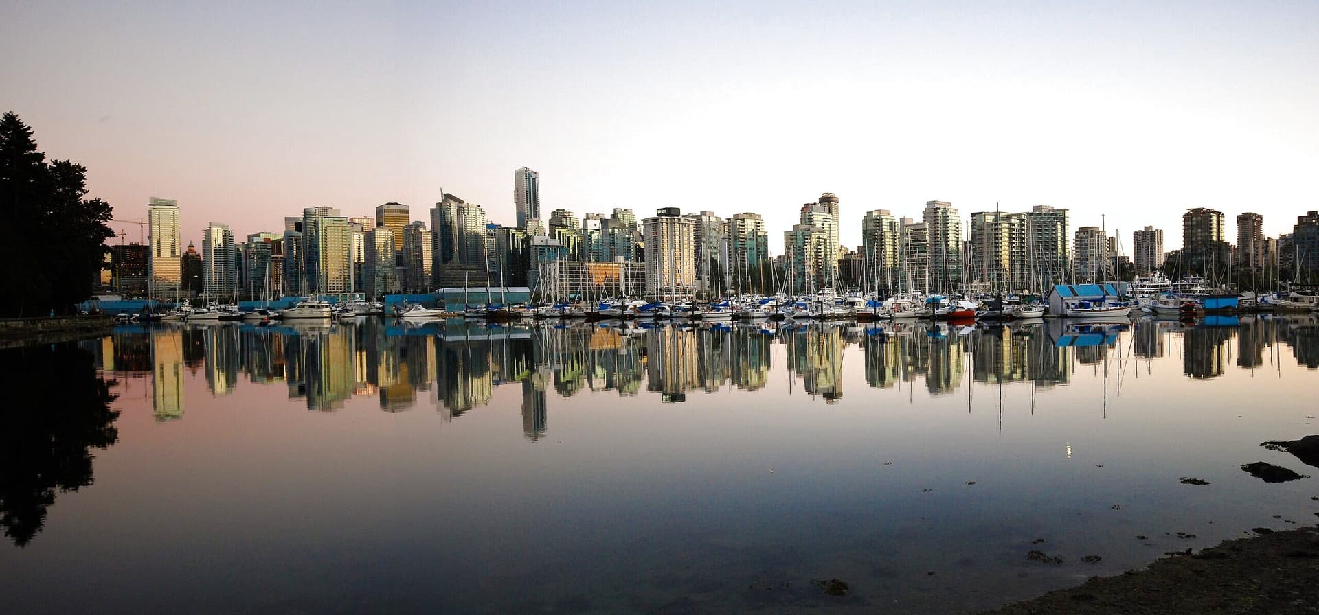 Downtown Vancouver towers reflected in the still water of Coal Harbour at dusk.